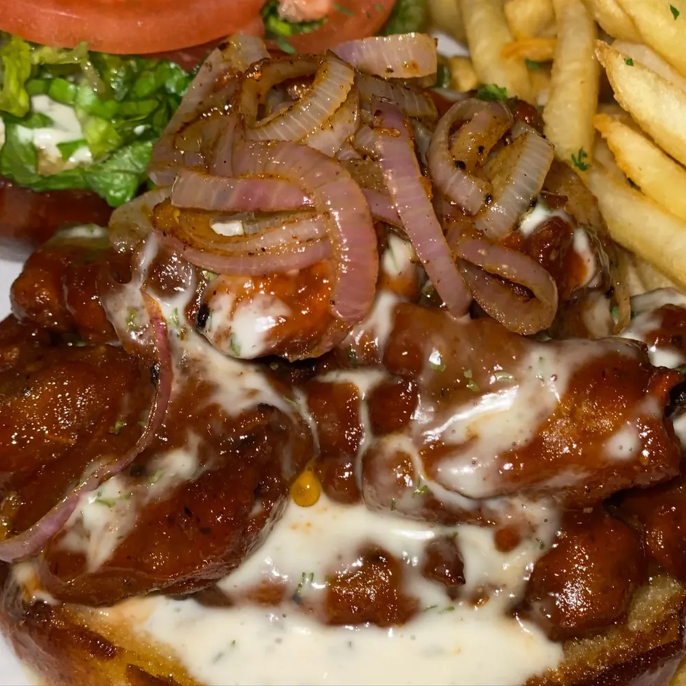 Fried oyster mushroom chk’n in BBQ sauce with grilled onions and a ranch drizzle, served with fries